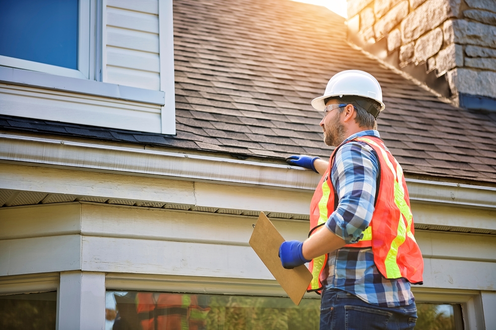 A,man,with,hard,hat,standing,on,steps,inspecting,house